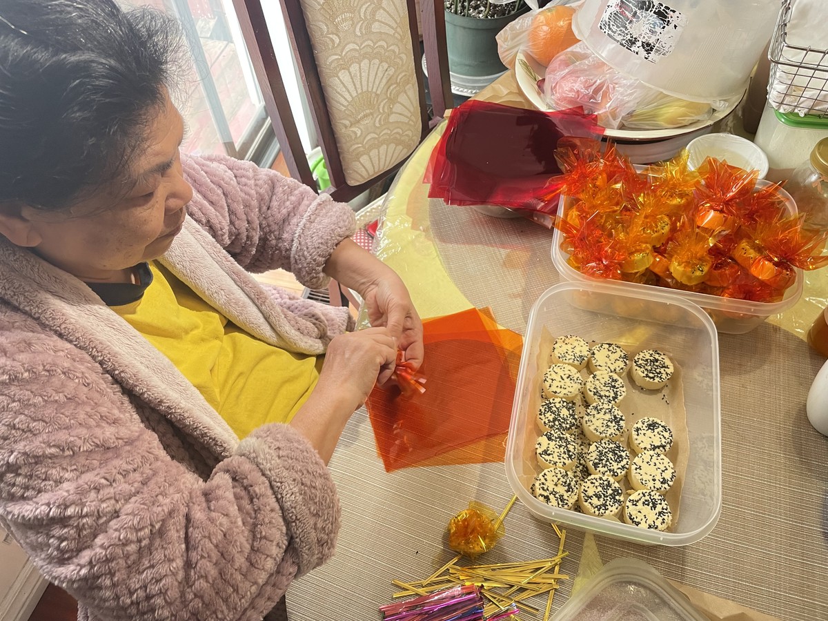 Woman wrapping homemade sweets at a kitchen table.