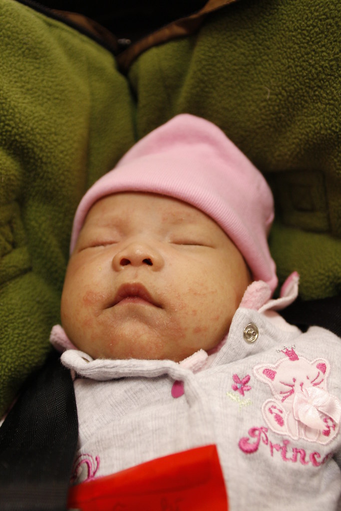 Sleeping newborn baby wearing a pink hat and pink outfit.